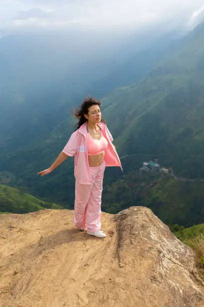Photo of Girl enjoys a mountain view while standing on a cliff