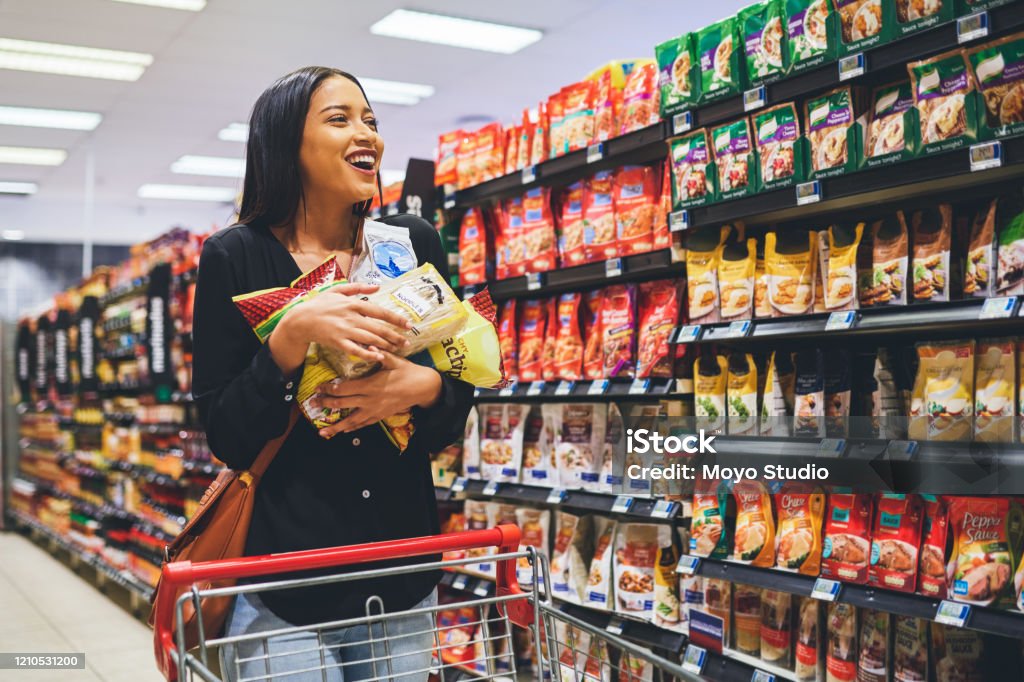 Look at these prices, I've got to get more Shot of a young woman shopping in a grocery store Supermarket Stock Photo