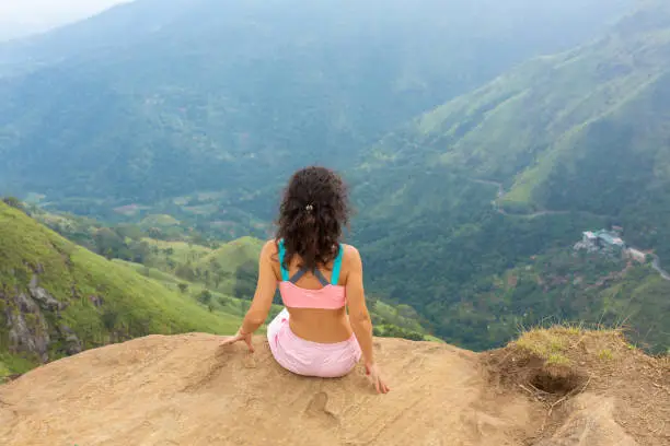 Photo of Girl enjoys a mountain view while standing on a cliff