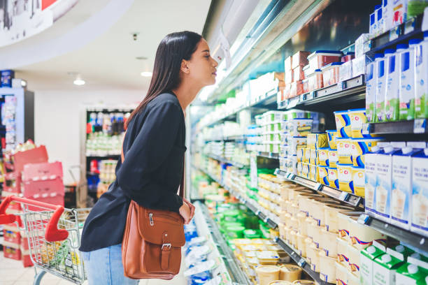 Looking for a lactose free alternative... Shot of a young woman shopping in a grocery store margarine stock pictures, royalty-free photos & images