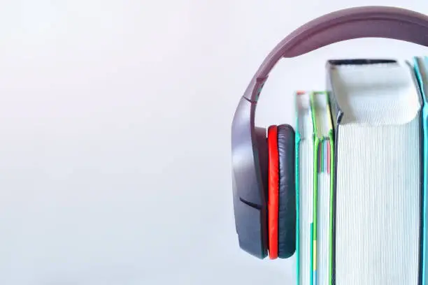 Photo of Modern headphones and books on table on white background. Concept of audiobook.