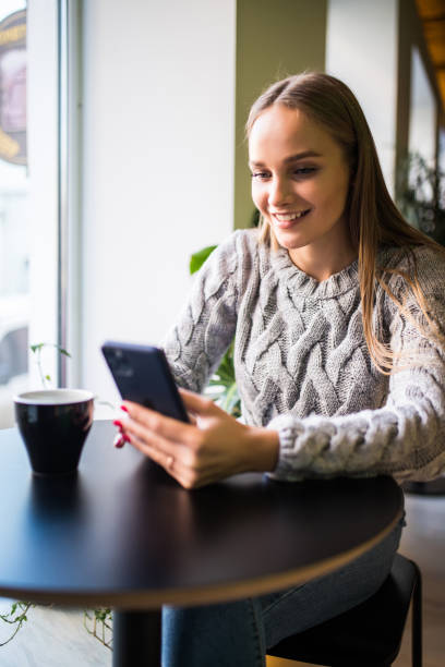 istock Young woman using mobile phone in coffee shop 1210532523