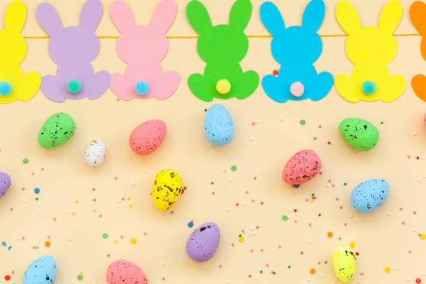 istock Colorful Easter eggs and handmade bunny easter garland on beige background. Top view, flat lay. 1210534574