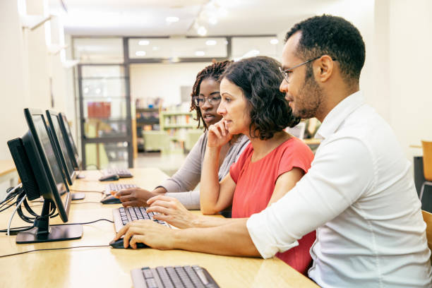 istock Diverse adult college mates working together in computer class 1210535001
