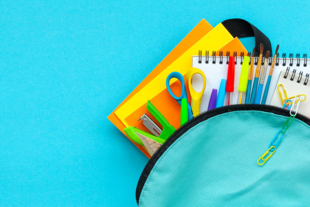 Concept back to school. Full turquoise School Backpack with supplies on blue background. FLat lay. stock photo