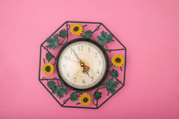 Close up clock set on pink background, time concept with copy space.