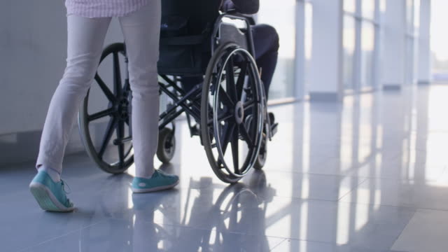 Woman carrying invalid in wheelchair