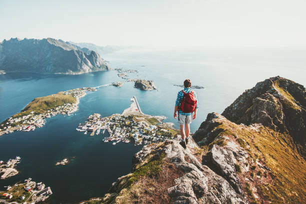 hombre viajero senderismo en la cresta de la montaña reinebringen en noruega aventura de estilo de vida viajando al aire libre vacaciones de verano disfrutando de vista aérea islas lofoten - norte de noruega fotografías e imágenes de stock