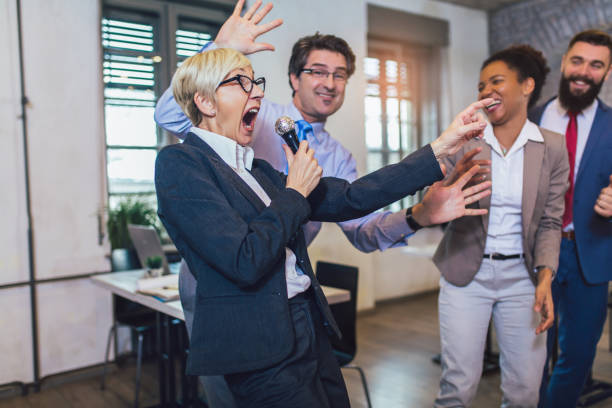 istock Business people making team training exercise during team building seminar singing karaoke. 1210537063