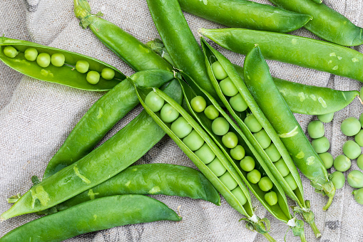Green, tender, fresh and raw peas. Close-up and top view. Rustic appearance. Rustic appearance. Black background.