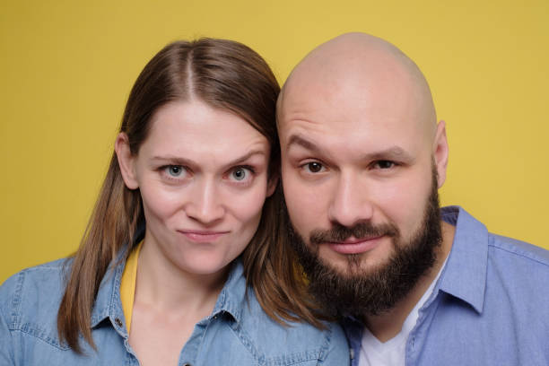 istock Young caucasian couple looking with doubt at camera having sceptical faces. 1210538029