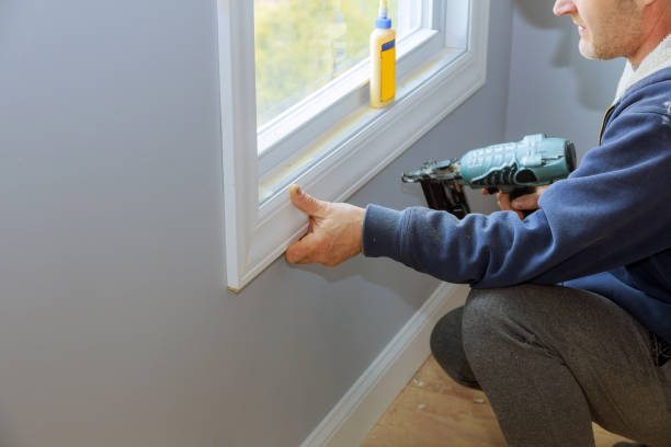 istock Carpenter using air nail gun to moldings for window 1210538585