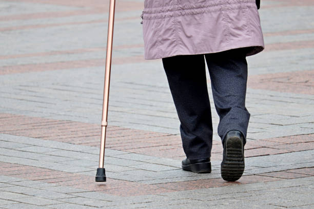 istock Limping woman walking with a cane down the street 1210540136