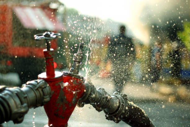 Water splashes from the fire hose and hydrant connections. Firefighters Work Concept.