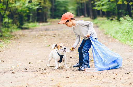 Concepto del día de la Tierra con el niño y el parque de limpieza de perros que recogen botellas de plástico photo