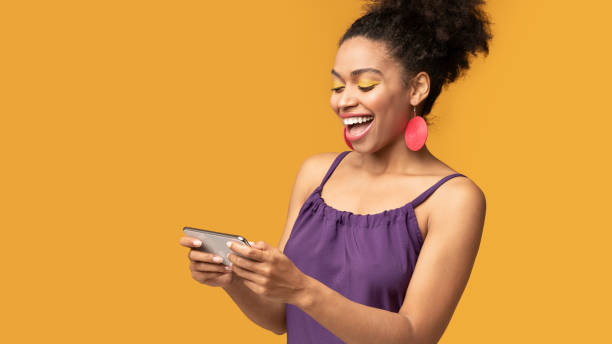 istock Afro woman using mobile phone playing games at studio 1210546930