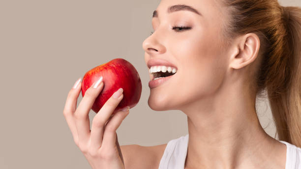 istock Young Lady Biting Red Apple On Beige Studio Background, Panorama 1210548250