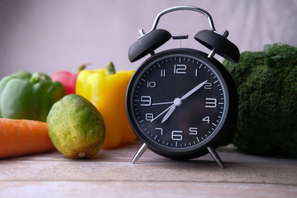 istock Close up of alarm clock and vegetable on table 1210548267