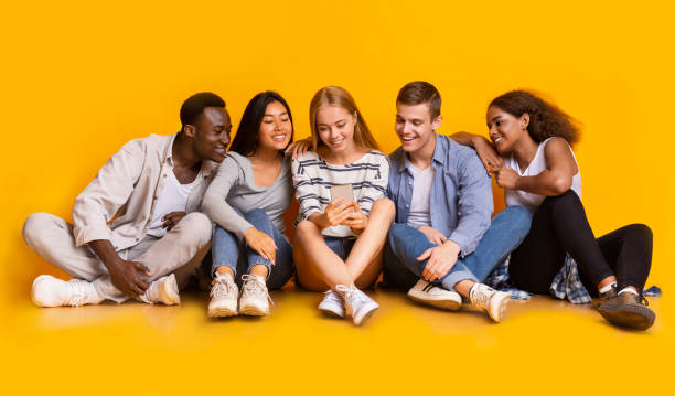 istock Teenagers sitting on floor and looking at smartphone screen 1210548541