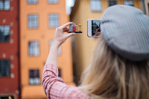Modern woman taking photo of souvenir who is exactly the same as the buildings in Gamla Stan