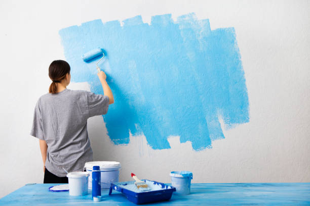 istock Woman painting interior wall with paint roller 1210549999