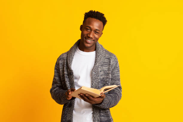 istock Smiling young african guy reading book for education 1210550219