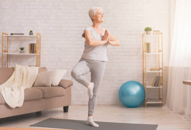 istock Senior woman doing yoga tree pose at home, free space 1210550241