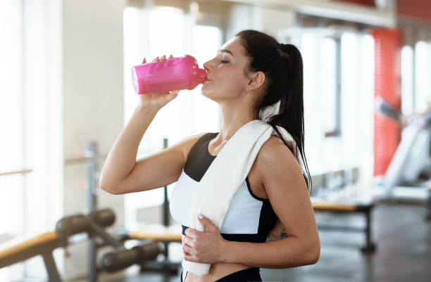 istock Keep hydrated. Young woman drinking water or protein cocktail in gym 1210550294