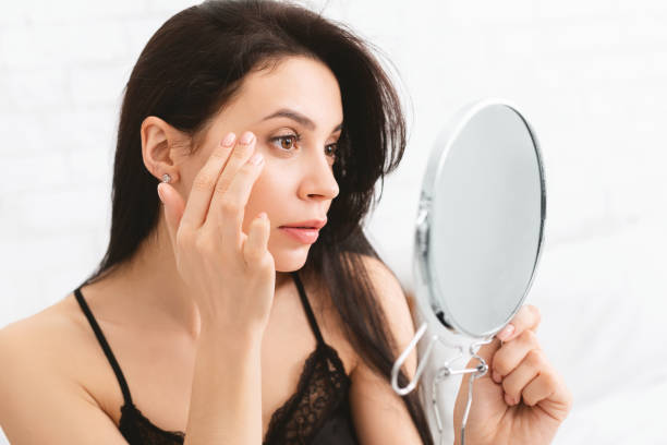 istock Young woman checking her wrinkles with mirror 1210550331