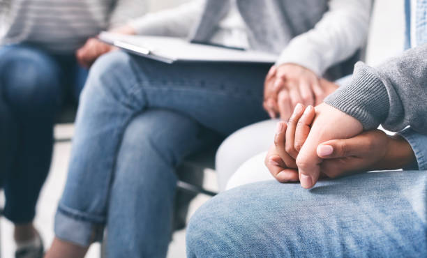 istock Group of addicted people holding hands supporting each other in rehab 1210550355