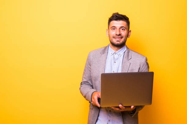 istock Young man with a laptop isolated on a yellow background 1210550910