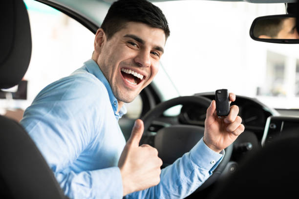 istock Man Showing Car Key And Thumb Up Sitting In Auto 1210550972