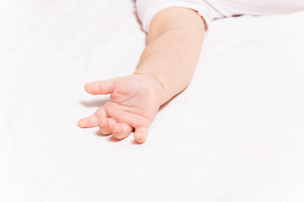 istock Little infant hand laying on the bed white sheet 1210551152