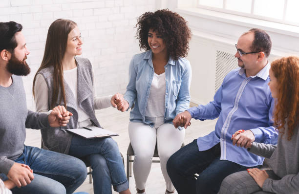 istock Young multi-cultural group of people holding hands during therapy session 1210551351
