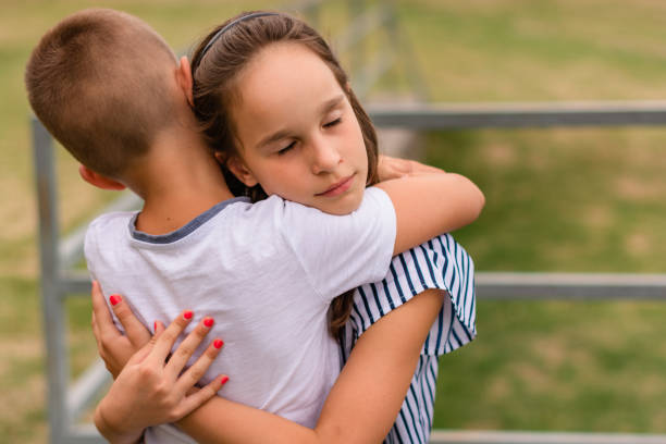 istock Brother and sister hugging outdoors 1210551375