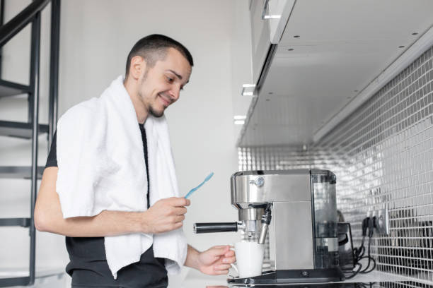 istock A young guy is going to work in the morning. Brushes teeth near a coffee machine while waiting for a cup of coffee 1210551748