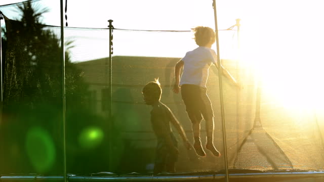 Little boys jumping inside trampoline outdoors