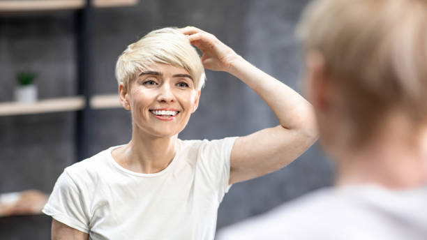 istock Happy Lady Touching Hair Looking In Mirror Standing In Bathroom 1210553330