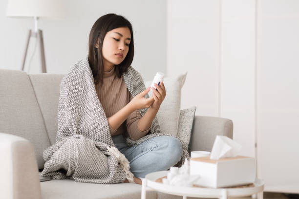 istock Girl with cold and flu reading instructions on medicine bottle 1210553743