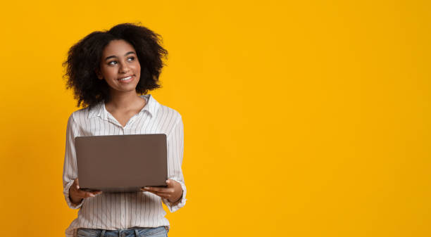istock Pensive Afro Woman With Laptop Computer Looking Away On Yellow Background 1210554448