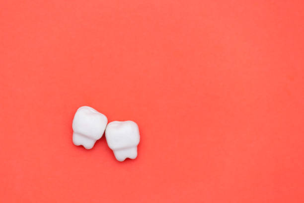 istock White tooth, space for text on color red background. Healthy dental teeth concept. 1210554622