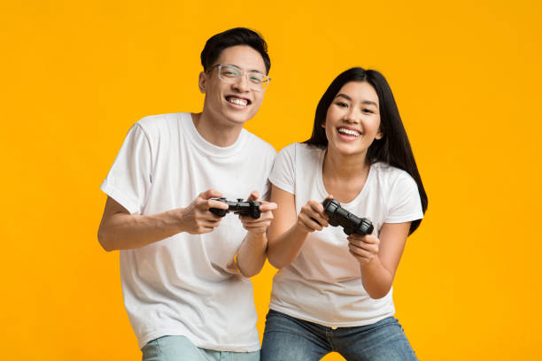 ジョイスティックでビデオゲームをプレイギャンブルアジアのカップル - beautiful business lifestyles studio shot ストックフォトと画像