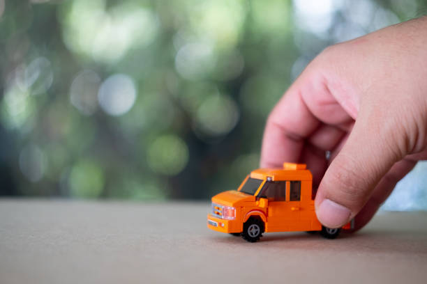 istock Child playing with a orange toy truck on table 1210555270