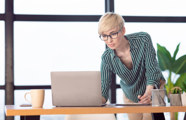 istock Successful Business Lady Using Laptop Taking Notes Standing In Office 1210555413