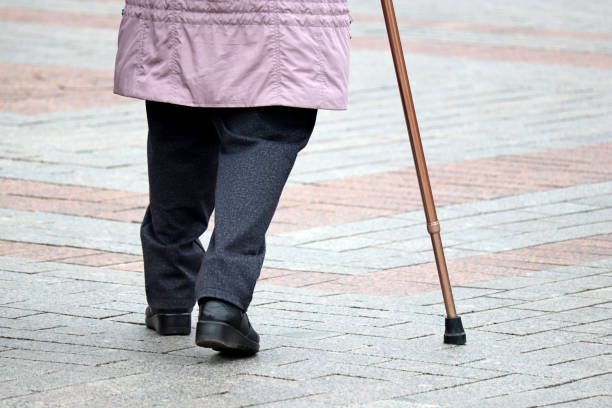 istock Limping woman walking with a cane down the street 1210556712