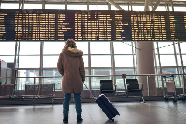 istock Woman looking airport arrival departure board 1210556780