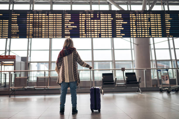Woman reading departure board on airport Woman reading departure board on airport cancellation photos stock pictures, royalty-free photos & images