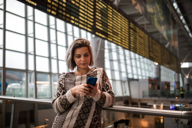 istock Young woman using smart phone on airport 1210557047