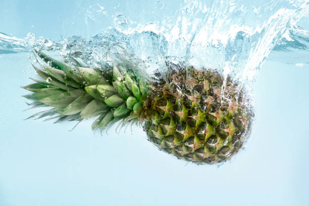 istock Exotic freshness. Juicy pineapple splashing into pure water on blue background 1210558637