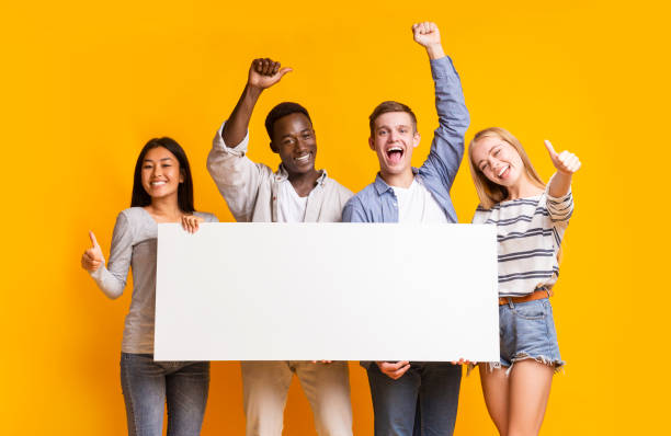 istock Joyful teenagers with empty billboard showing thumbs up 1210559126